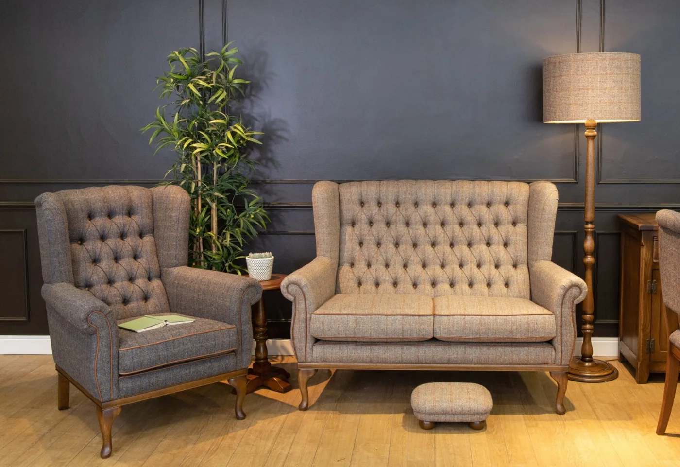 A Wood Bros armchair and sofa in tweed beside a floor lamp