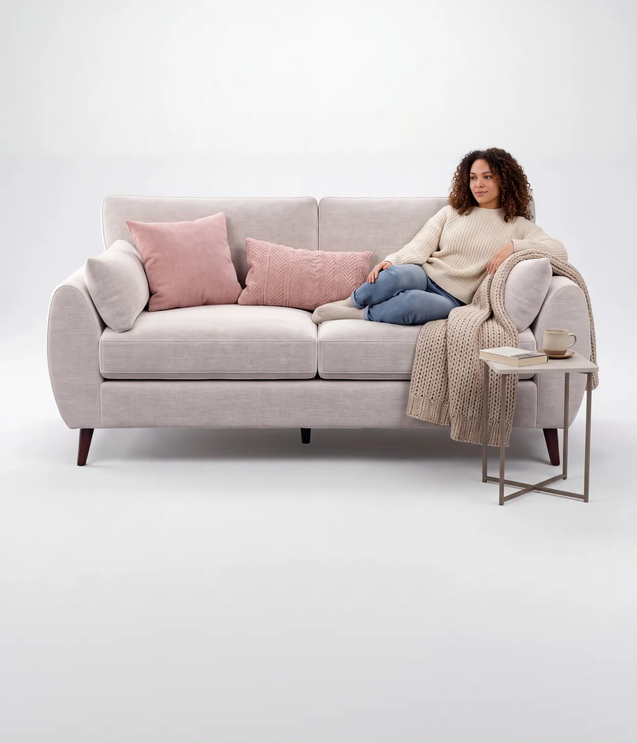 A woman relaxing on a cream sofa with cushions and a knitted throw