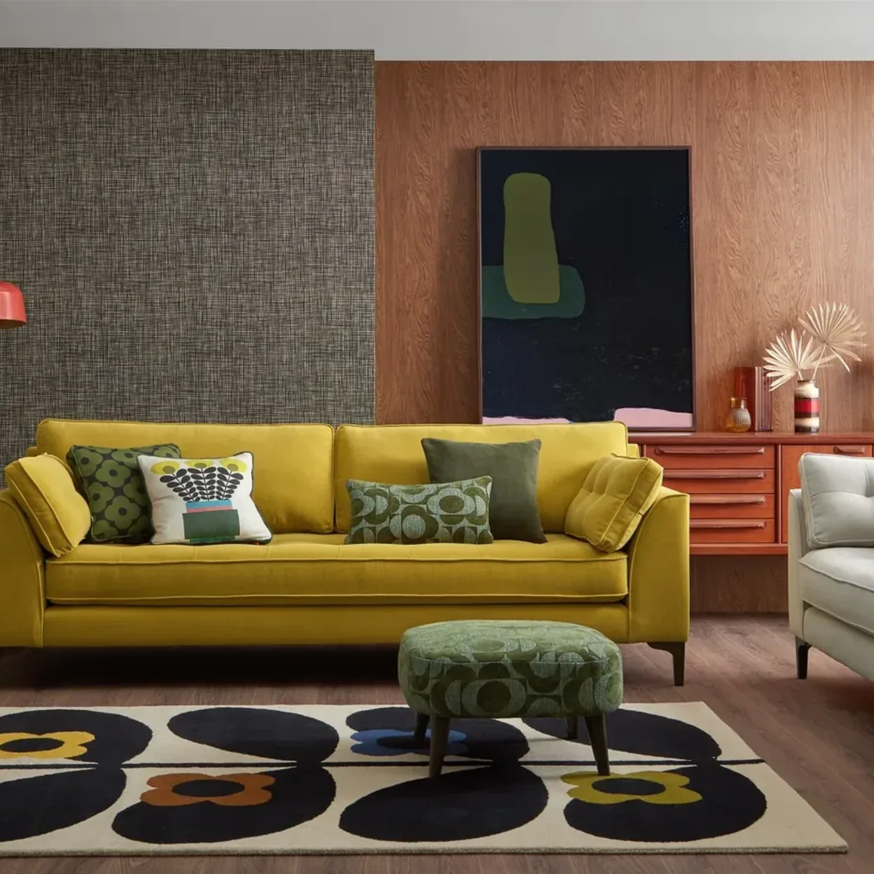 A yellow sofa on a bold patterned rug in a colourful living room