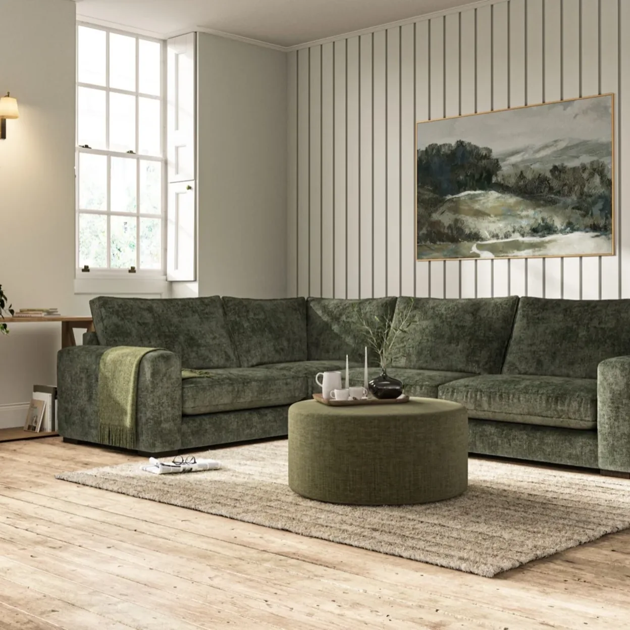 A sage green corner sofa in a paneled living room